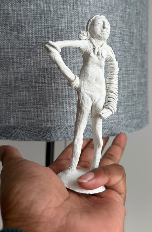 A hand-built clay rendition of the Dancing Girl of Mohenjo-daro — a standing figure with one hand set on her hip and the opposite arm stacked with bangles, held upright in an open palm